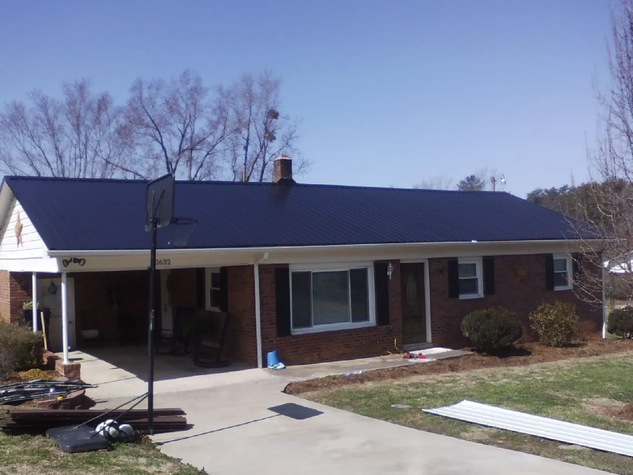 Finished dark blue metal roof on a brick ranch with a carport in North Smithfield