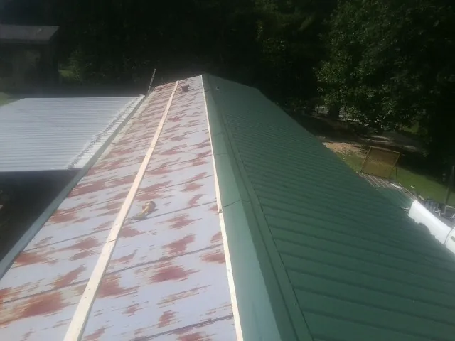 Old rusted panels beside newly installed green metal roofing — Wind Damage Roof Repair by Roofing Brothers in North Smithfield