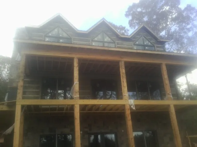 Dormers and porch framing on a large log home under construction — Roof Coating work by our crew in North Smithfield