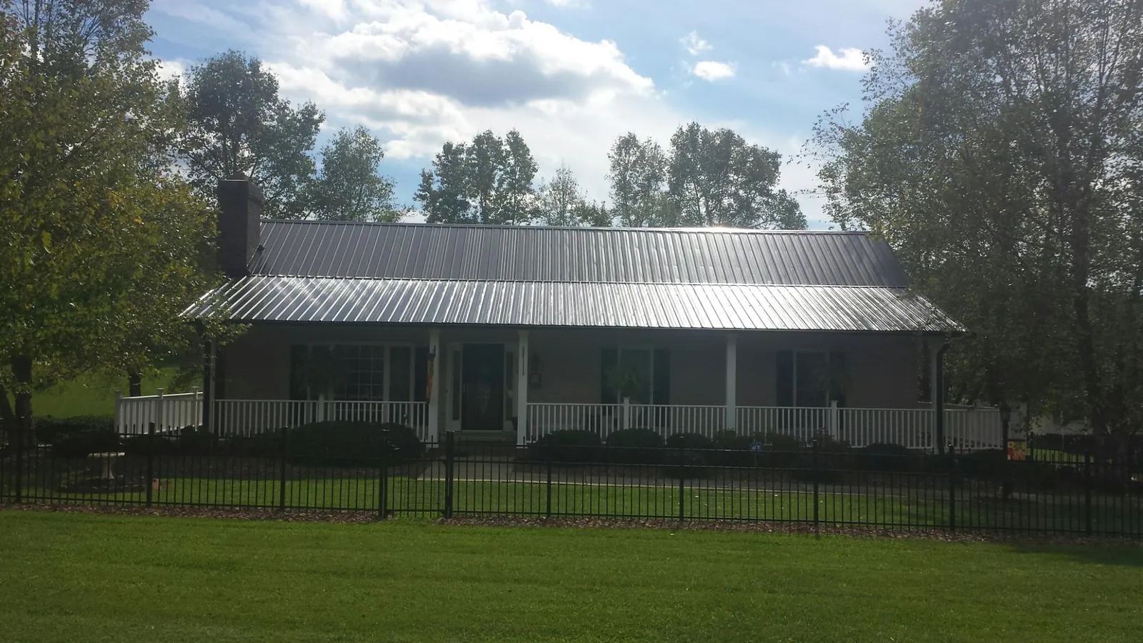 Gray metal roof on a brick ranch with a full width front porch — Gutter Guard Installation work by our crew in North Smithfield
