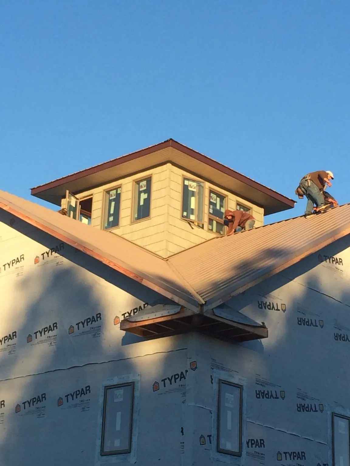 Roofers working around a rooftop cupola on a new metal roof at sunset — Roof Waterproofing in North Smithfield by Roofing Brothers